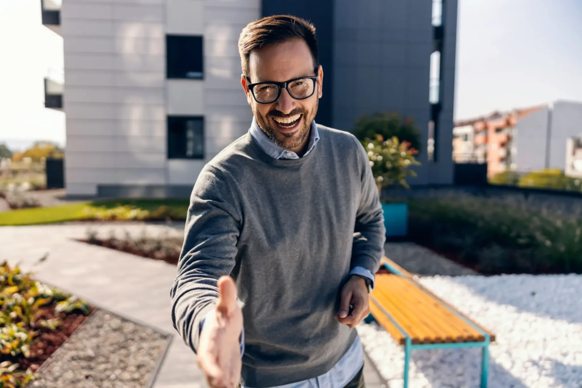 Man extending hand for handshake outdoors.