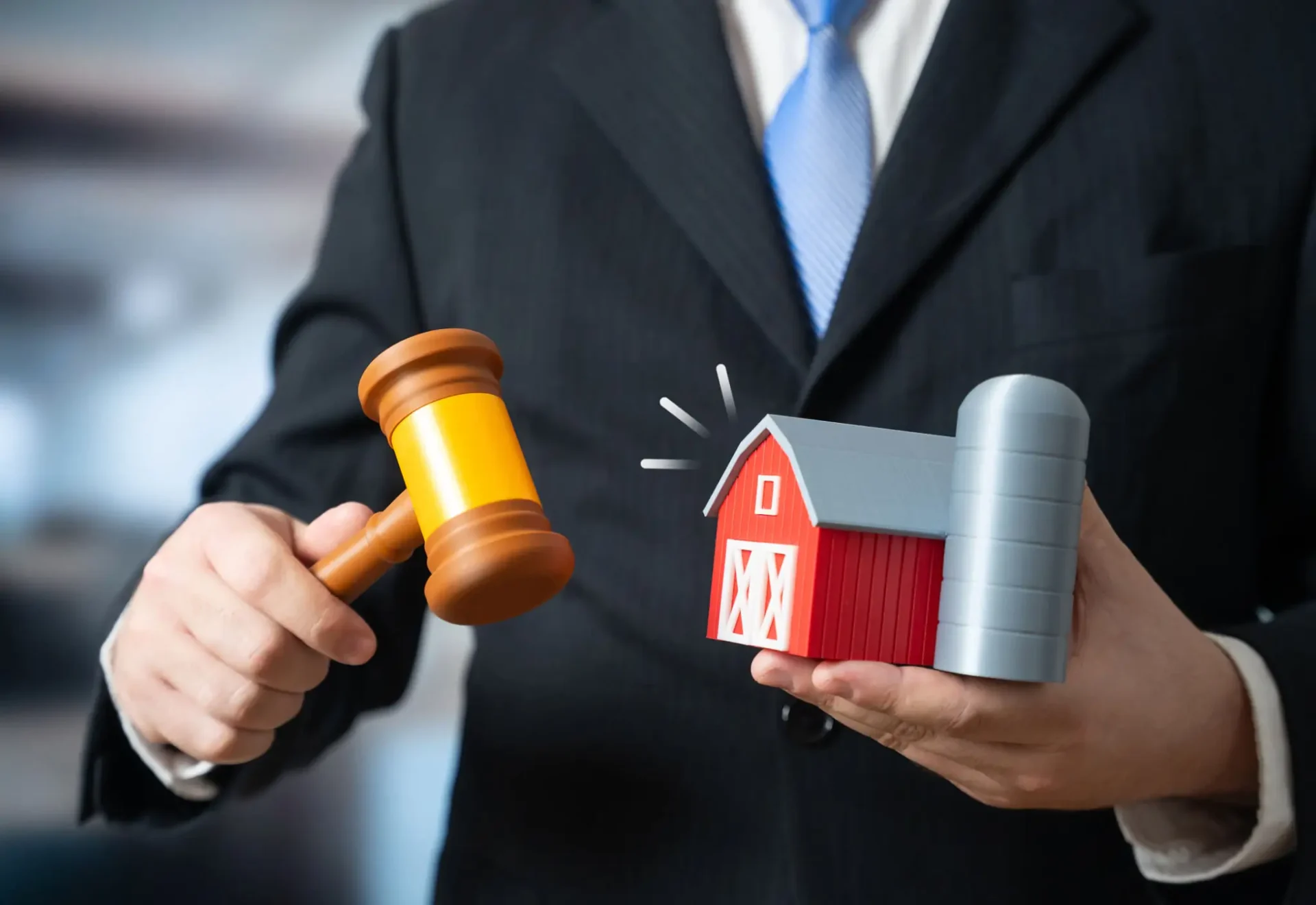 Man holding gavel and small red barn.