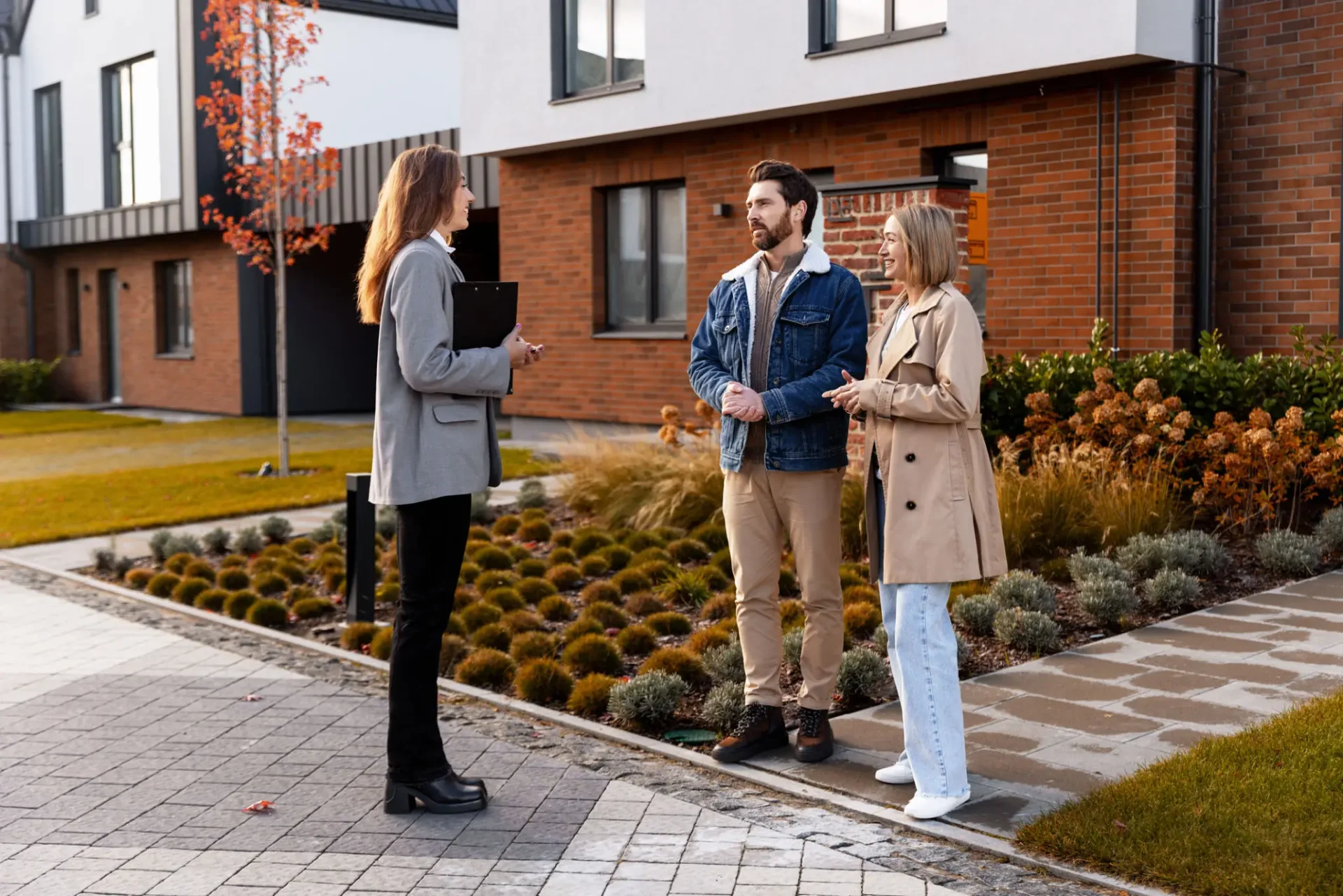 Real estate agent with couple outside house.