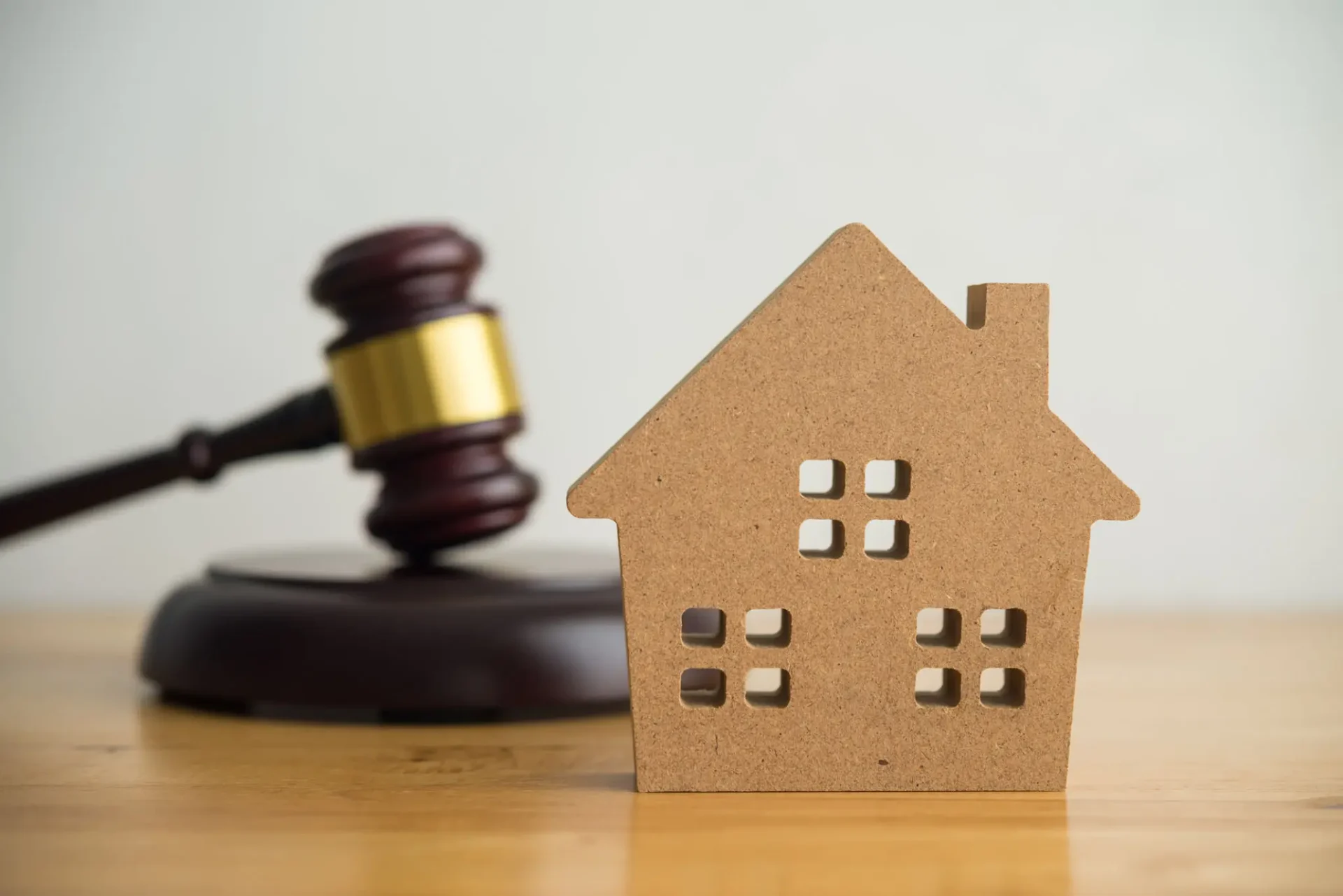 Gavel beside cardboard house on table.