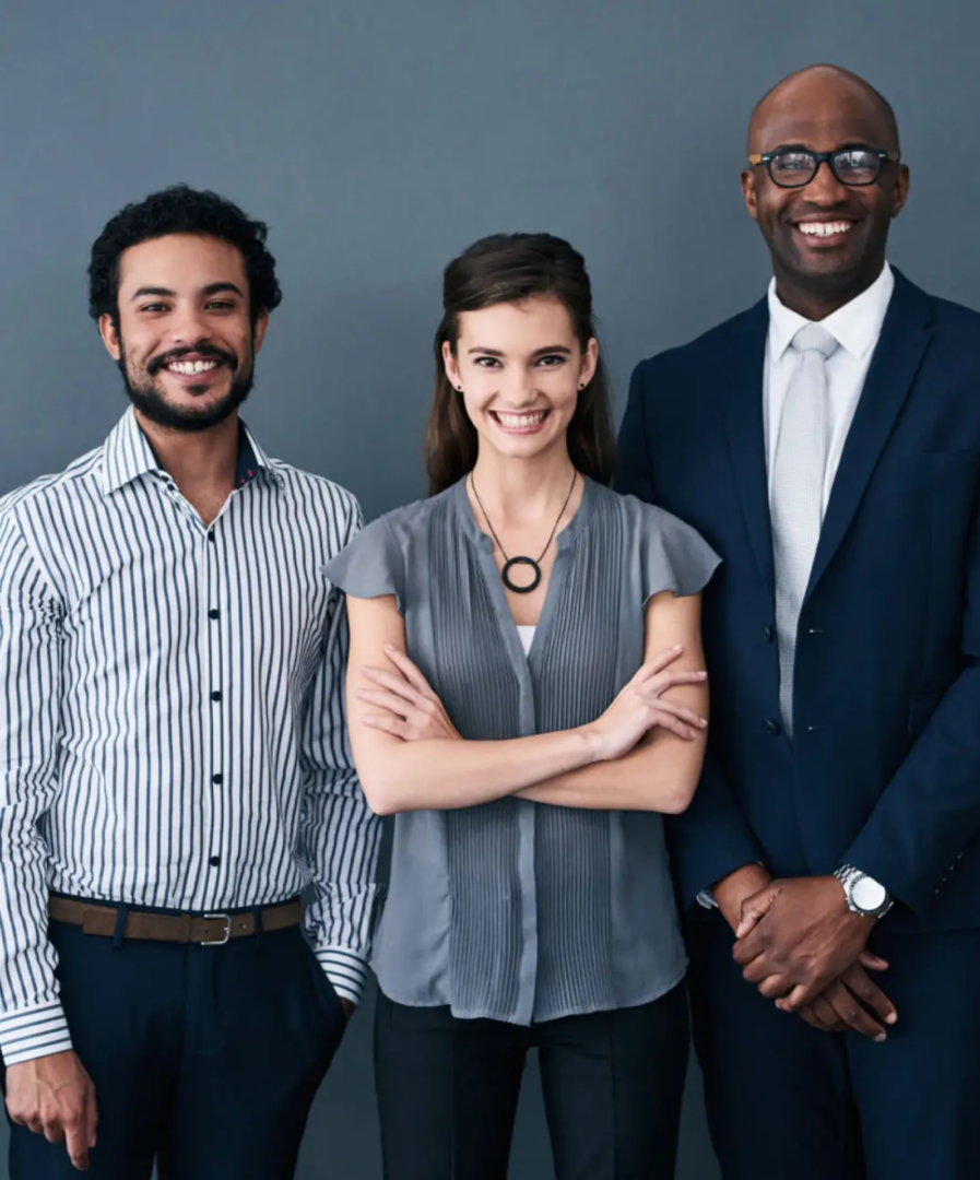 Three professionals smiling in business attire.