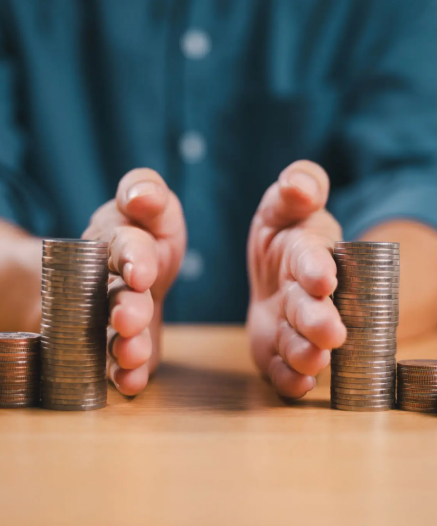 Hands arranging stacks of coins on table.