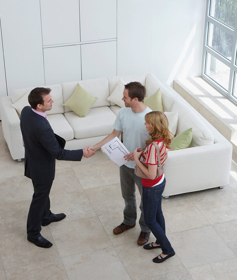 Real estate agent shaking hands with couple.