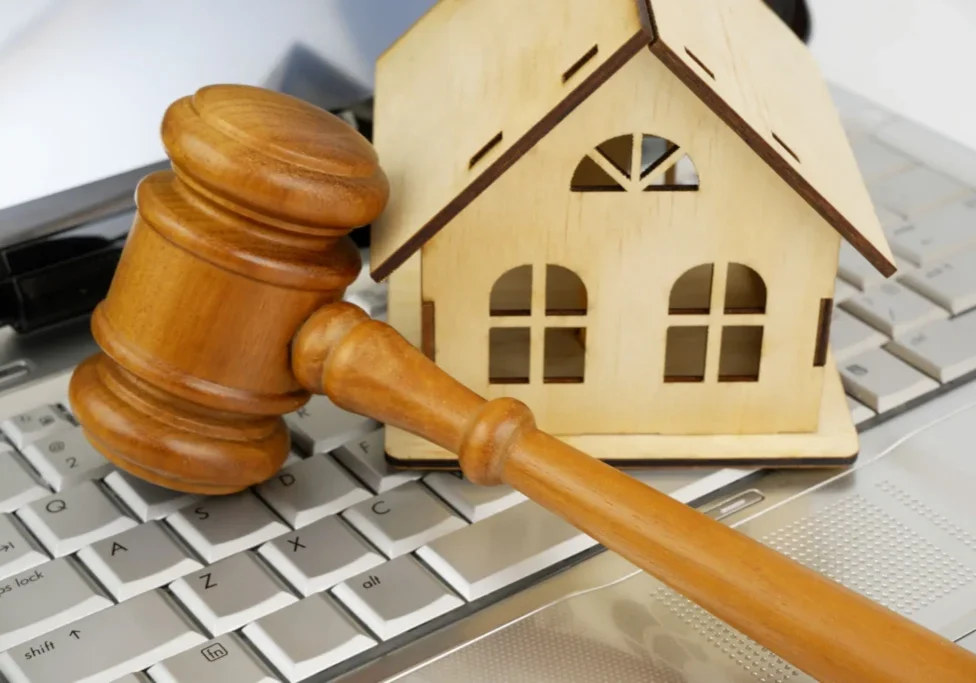 Gavel and house model on laptop keyboard.